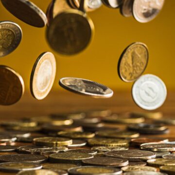 silver-golden-coins-falling-coins-wooden-table (1)