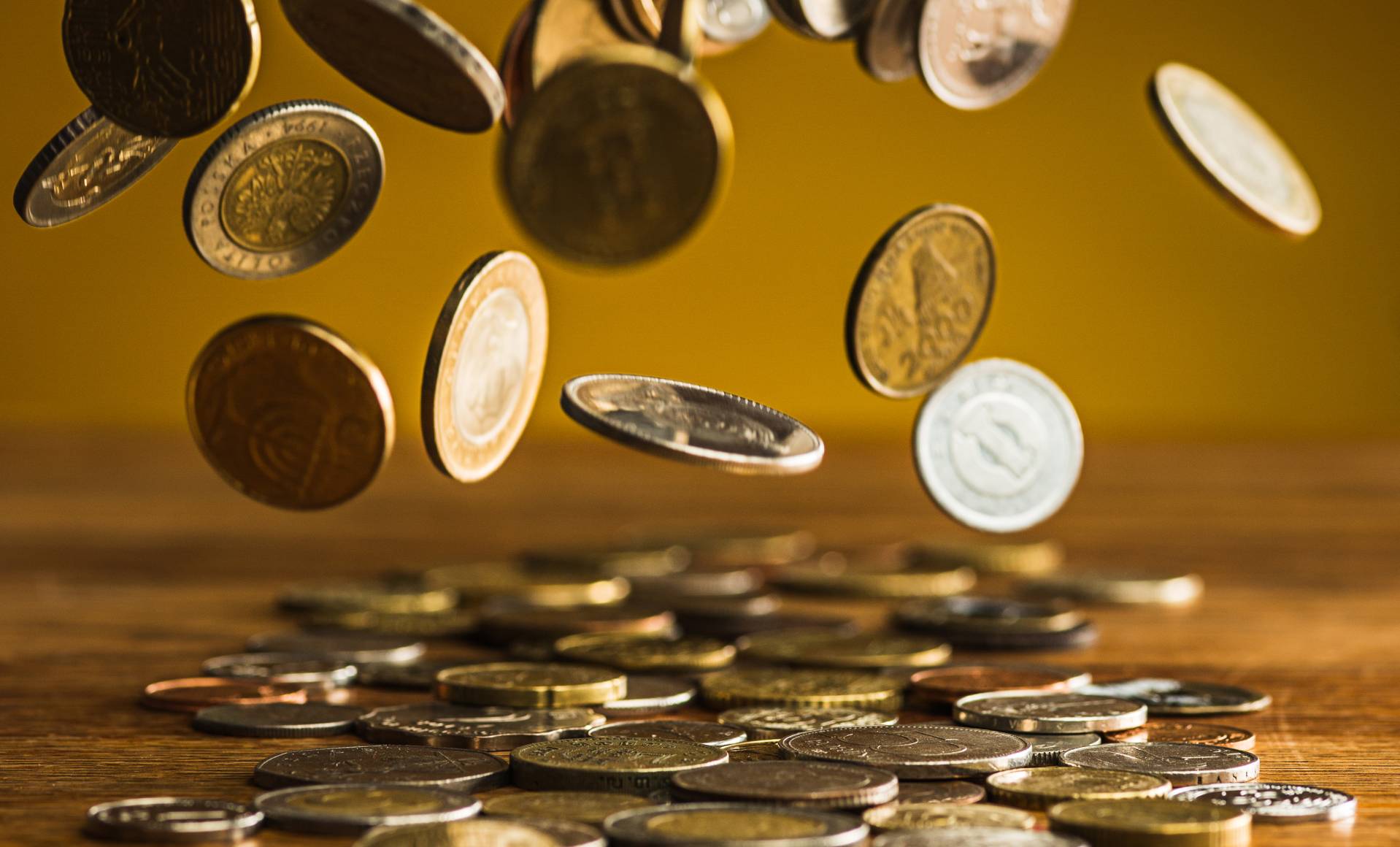 silver-golden-coins-falling-coins-wooden-table (1)